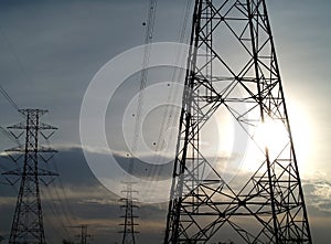 silhouette of steel framework of high voltage pylon tower with electric transmission power lines and evening sunset sky