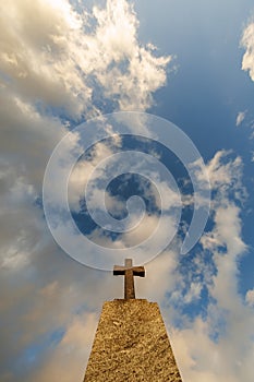 silhouette of stone grave cross against the background of a blue evening sky with clouds