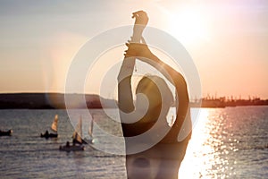 Silhouette of a strong confident woman on the seashore with a view of beautiful yachts. Portrait of a thin girl in a black dress