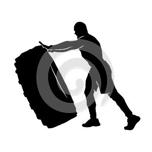 Silhouette of a strong man lifting big rubber tire.