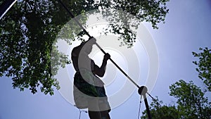 Silhouette of strong and muscular man doing Muscle-up on horizontal bar in slow motion on the blue sky and sun