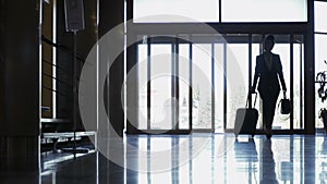 Silhouette of stylish businesswoman with suitcase just arrived in a hotel