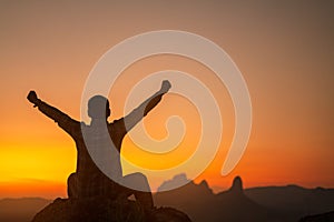 Silhouette of success man hiker outstretched arms on top of the mountain with beautiful sunset.Concept of adventure travel