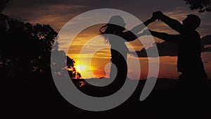 Silhouette, sunset and couple dancing in nature, love and happiness for romance