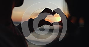 Silhouette, sunset and hands of couple with heart shape at the beach as love on holiday or tropical vacation together