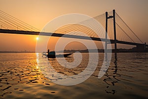 Silhouette sunset of Vidyasagar bridge with a boat on river Hooghly