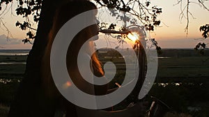 Silhouette at sunset young beautiful red-haired girl playing saxophoneon nature, a woman blowing into the pipe, concept hobby, mus