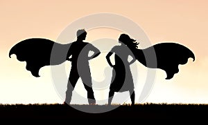 Silhouette of SuperHero Man and Woman Couple in Capes Standing Strong