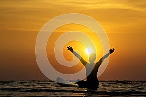 Silhouette of surf man sit on a surfboard, open arms.