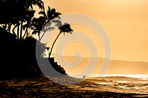 Silhouette of a surfer in the distance at sunset on Sunset Beach, Hawaii