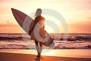 Silhouette surfer girl on the beach at sunset