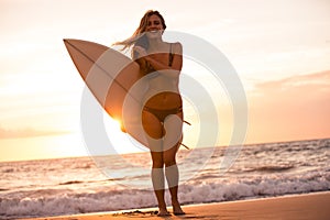 Silhouette surfer girl on the beach at sunset