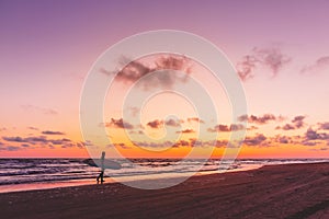 Silhouette of surfer girl with surfboard on a beach at sunset. Surfer and ocean