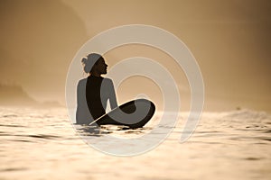Silhouette of a surfer girl in the waters