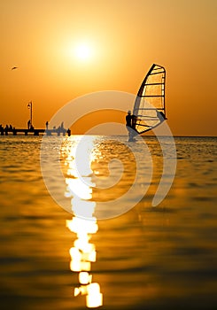 Silhouette of surfer at sunset passing by