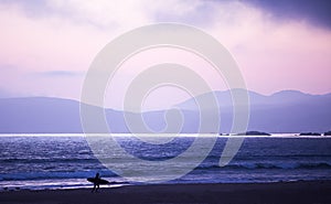 Silhouette, of Surfer walking on the beach at sunset. San Simeon beach, southern California