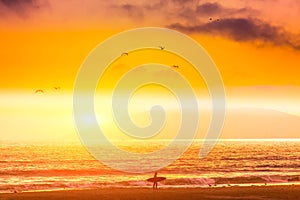 Silhouette, of Surfer walking on the beach at sunset. San Simeon beach, southern California