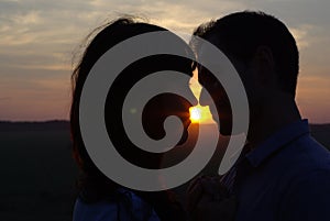 Silhouette sweethearts kissing at sunset