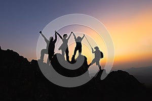 Silhouette Teamwork of four hiker helping each other on top of mountain climbing team beautiful sunrise. Teamwork friendship