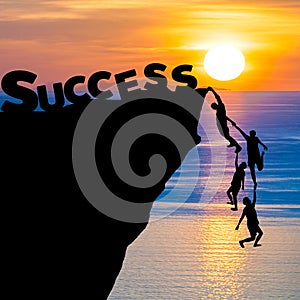 Silhouette teamwork of people climbs into cliff to reach the word Success business concept