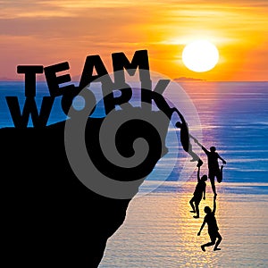 Silhouette teamwork of people climbs into cliff to reach the word TEAM WORK with sunrise