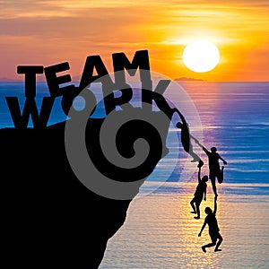 Silhouette teamwork of people climbs into cliff to reach the word TEAM WORK with sunrise photo