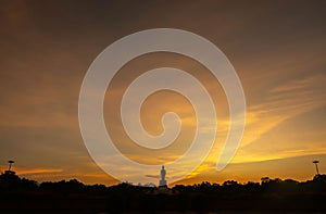 Silhouette technique under golden twilight evening sky with Walking Buddha statue in Thailand