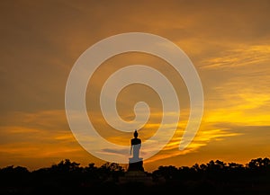 Silhouette technique under golden twilight evening sky with Walking Buddha statue in Thailand