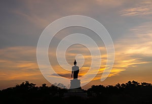 Silhouette technique under golden twilight evening sky with Walking Buddha statue in Thailand