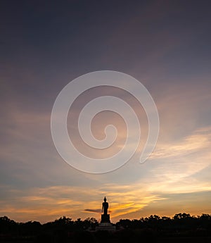 Silhouette technique under golden twilight evening sky with Walking Buddha statue in Thailand