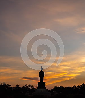 Silhouette technique under golden twilight evening sky with Walking Buddha statue in Thailand