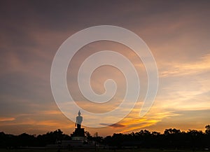 Silhouette technique under golden twilight evening sky with Walking Buddha statue in Thailand