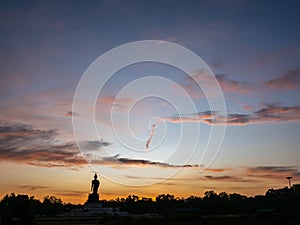 Silhouette technique under golden twilight evening sky with Walking Buddha statue in Thailand