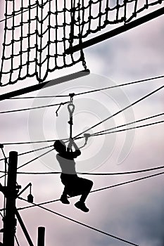 Silhouette of a teenage boy ziplining on zip line.