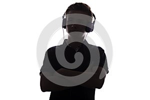 Silhouette of teenager listening to music in headphones, young man folded his arms on the chest on white isolated background