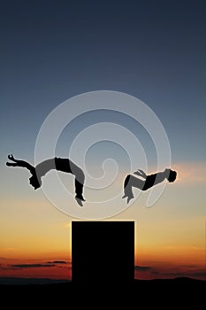 Silhouette of teenagers doing freerunning in sunset