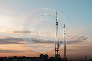 Silhouette, telecommunication towers with TV antennas and satellite dish in sunset, panorama composition