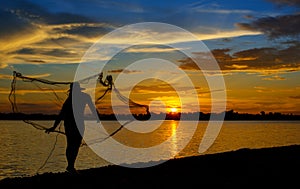 Silhouette of Thai Fisherman catching the fish in twilight  Beautiful Sunset in the sky with sky blue and orange light of the sun