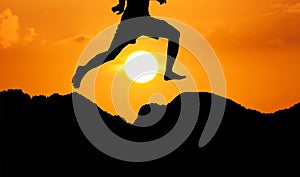 Silhouette of theyoung man jumpping at mountain yellow sunset ba photo