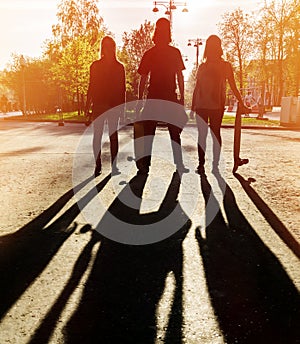 Silhouette three friends skateboarders in city