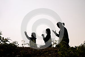 Silhouette of three woman kneeling down praying for worship God at white background. Christians pray to jesus christ for calmness