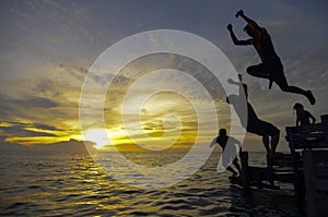 Silhouette of three young man jumping during awesome sunset