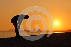 Silhouette of an tired sportsman at sunset photo