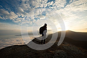 Silhouette of tourist hiker with backpack standing on the top of the mountain and looking at beautiful yellow autumn