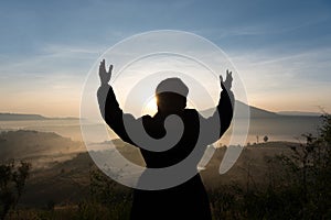 Silhouette tourist woman raised hand to sunrise and feeling happy