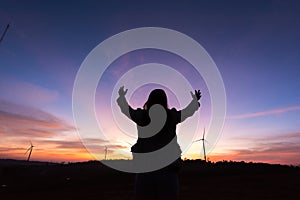 Silhouette tourist woman raised hand to sunset on the turbine at