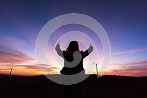 Silhouette tourist woman raised hand to sunset on the turbine at