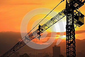 Silhouette Tower crane construction with worker in sunset and copy space add text