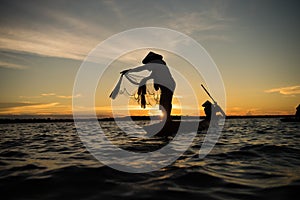 Silhouette of traditional fisherman throwing net fishing lake at