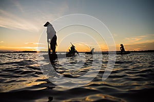 Silhouette of traditional fisherman throwing net fishing lake at